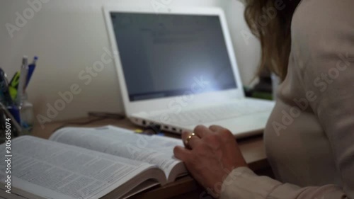 Uma mulher no escritório lendo livro e digitando no computador  photo