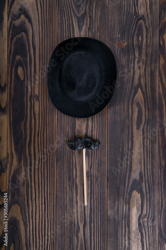 Men's hat and mustache in the form of lollipop  on wooden background.