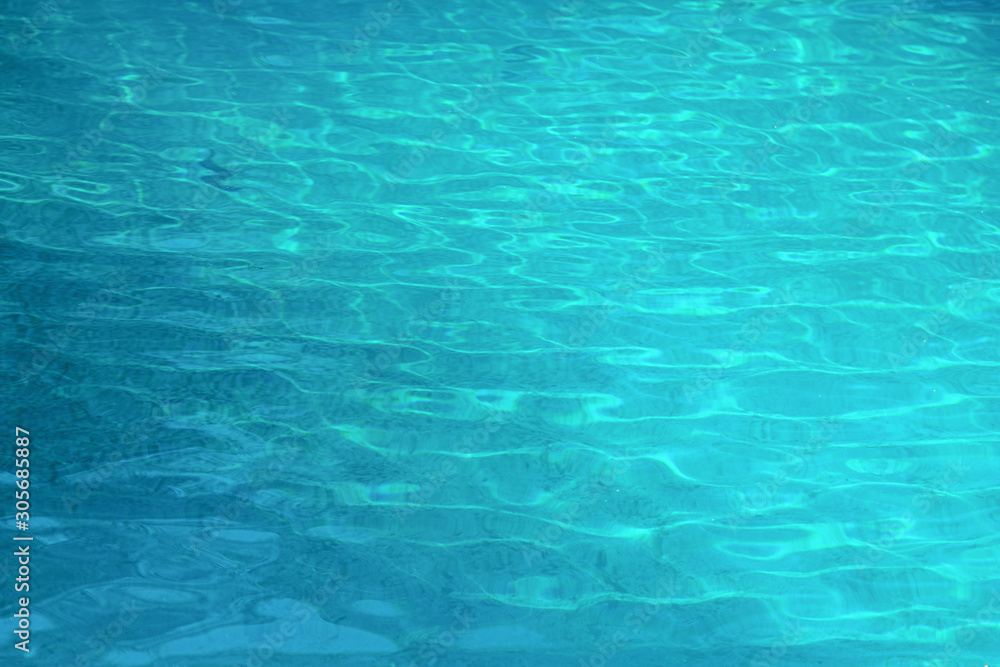 Blue wave ripple in swimming pool with sun light reflection on water surface