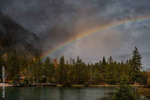 Rainbow over Turquoise colour lake South Tyrol  Italy   Alps. Reflection in water during rain  high ISO long exposure image 