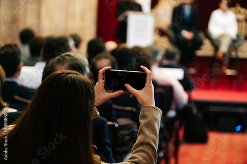 A woman takes a picture with a mobile phone in a meeting