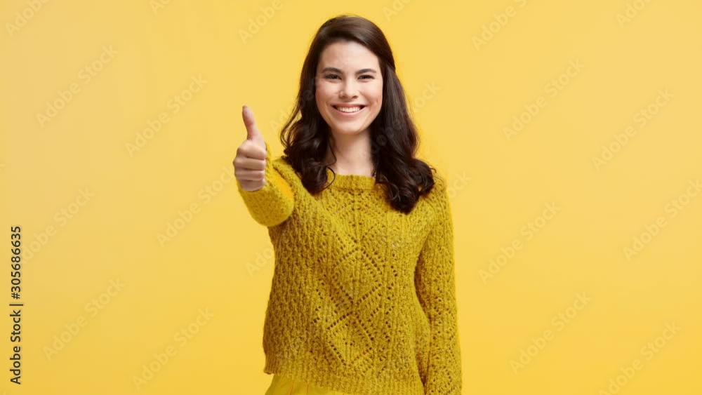 smiling girl in sweater showing thumb up isolated on yellow smiling girl in sweater showing thumb up isolated on yellow