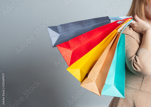 Girl with shopping bags on grey background with copy space