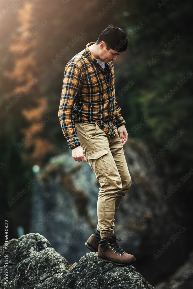 Male traveler standing on top of big rocks in Lago di Braies (Braies lake, Pragser wildsee)