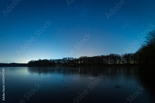 Sterne über dem See und Wald im Winter