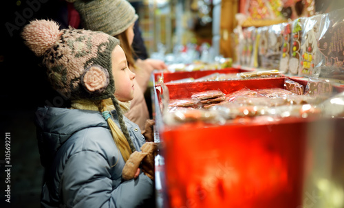 Cute young sisters choosing sweets on traditional Christmas market in Riga, Latvia. Kids buying candy and cookies on Xmas.