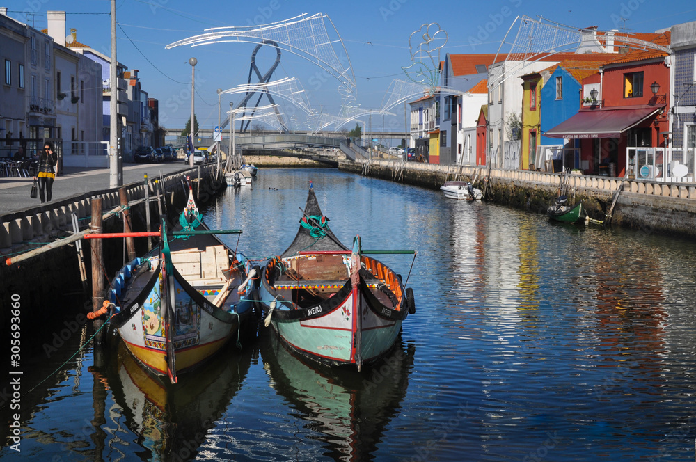 Traditional colored boats on the water, water canal and city. Colored houses by the river , moliceiros. Aveiro. Portugal. Europe.