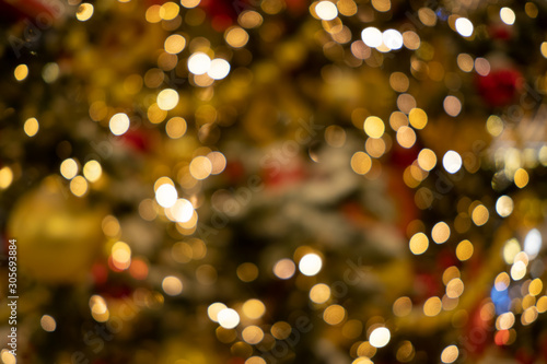 Holiday decorations, toys, garlands on a Christmas tree. Abstract blurred background with bokeh lights.