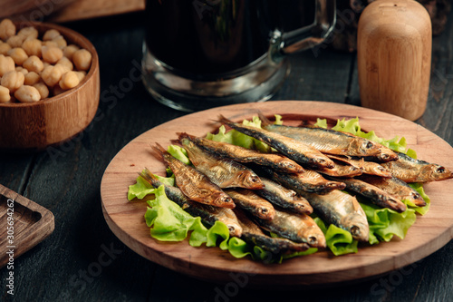 Obraz na plátně dried smoked sprat layered on lettuce leaves served on round wood platter