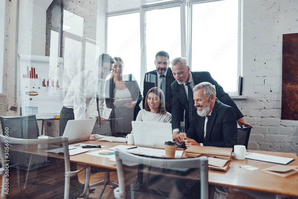 Self-driven business team analyzing sales using modern technologies while having staff meeting in the board room Self-driven business team analyzing sales using modern technologies while having staff meeting in the board room