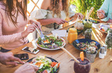 Hands view of young people eating brunch and drinking smoothies bowl with ecological straws in trendy bar restaurant - Healthy lifestyle, food trends concept - Focus on left woman hand, dish