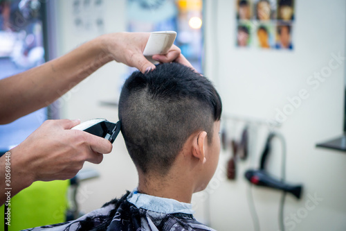 An Asian boy in the barbershop ,Boy getting haircut by barber in barbershop