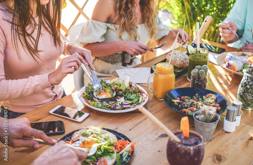 Hands view of young people eating brunch and drinking smoothies bowl with ecological straws in trendy bar restaurant - Healthy lifestyle, food trends concept - Focus on left woman hand, dish photo