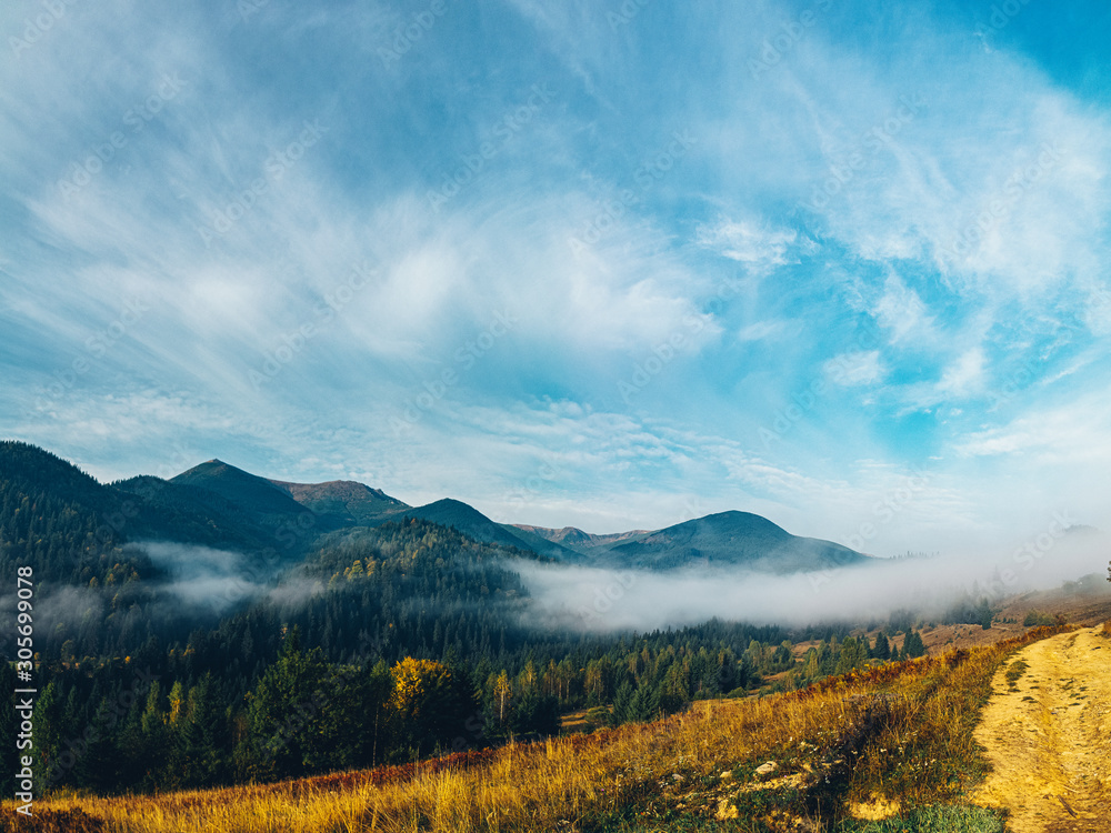 Aerial view amazing over of the Carpathian Mountains or Carpathians with Beautiful autumn landscape , sunrise, blue sky with white clouds, fog between the mountain slopes Aerial view amazing over of the Carpathian Mountains or Carpathians with Beautiful autumn landscape , sunrise, blue sky with white clouds, fog between the mountain slopes