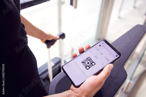 Close Up Of Male Passenger In Airport Looking At Digital Boarding Pass On Smart Phone photo