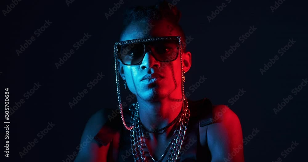 Young shirtless man posing wearing fancy goggles and chain necklace in ultraviolet light Young shirtless man posing wearing fancy goggles and chain necklace in ultraviolet light