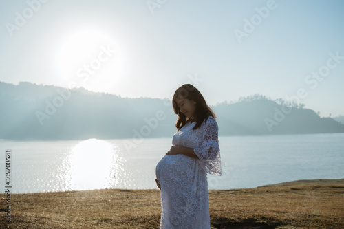 asian mother pregnant having fun at sunrise in the outdoor