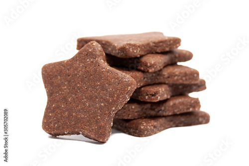 Delicious homemade chocolate and sugar cookies in the shape of stars, piled up on top of each other and one stands nearby, isolated on a white background. Selective focus. Holiday baking for family