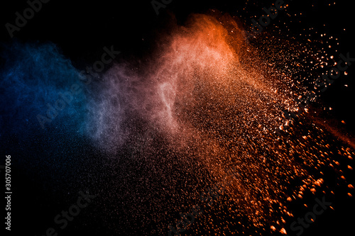Orange blue powder explosion on black background.Orange blue color dust splash clouds.