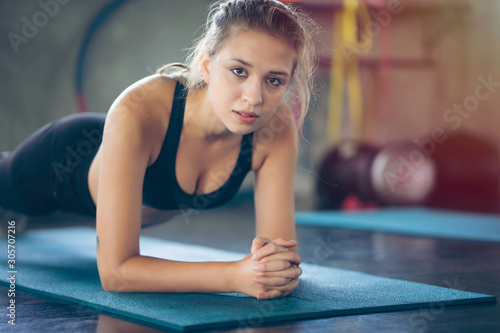 Young woman doing plank at gym or fitness  workout in middle of body to build muscle at belly stronger with serious face and concentrate her exercise. Under instructor control fat  diet and weight
