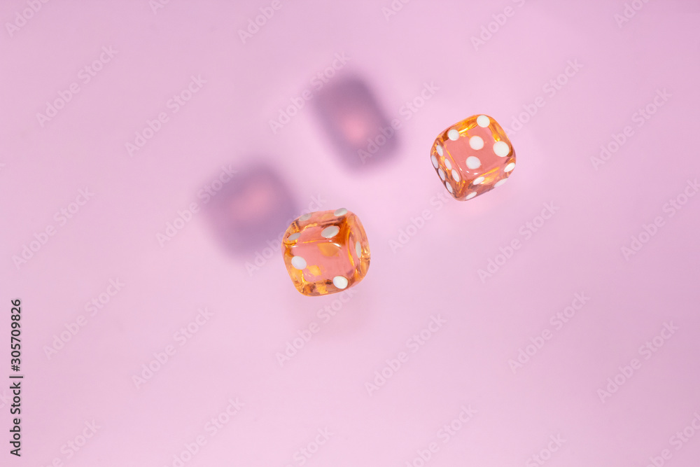 Two glass dice fall, bone to game on pink background. Concept for board games. Two glass dice fall, bone to game on pink background. Concept for board games.