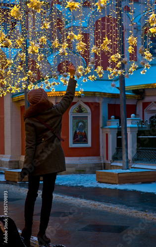 New Year decorations on Nikolskaya street in Moscow, Russia, Young woman touching New Year's decoration © Vladiri