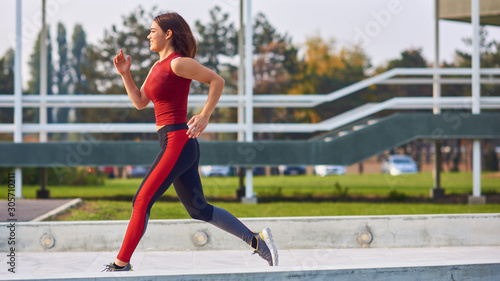 Fototapeta Naklejka Na Ścianę i Meble -  Young woman exercising / running in urban park.