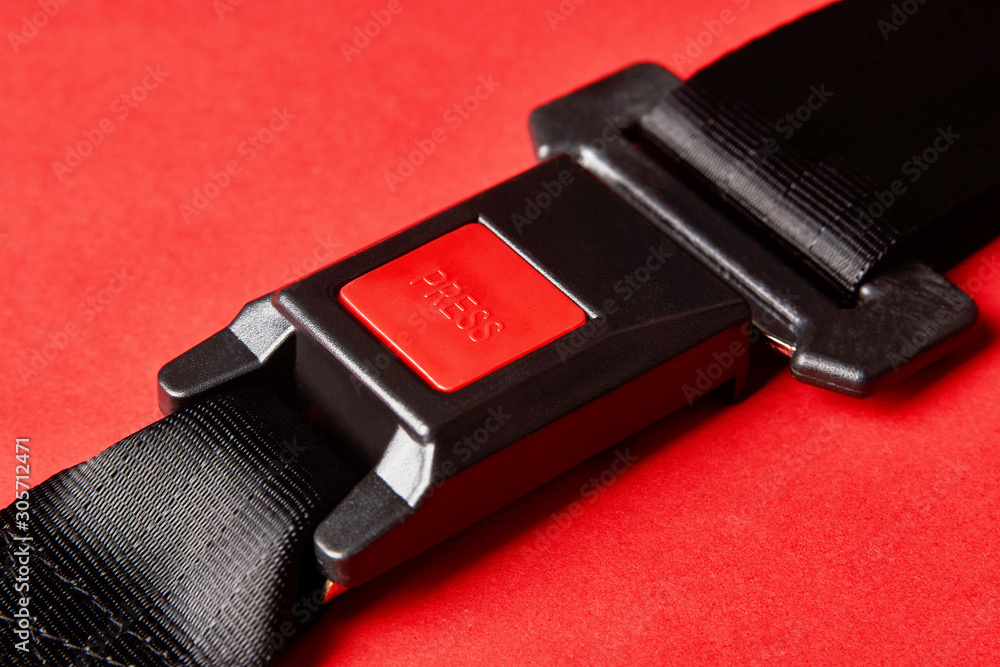 Fastened seat belt on red background with copy space, close-up Fastened seat belt on red background with copy space, close-up