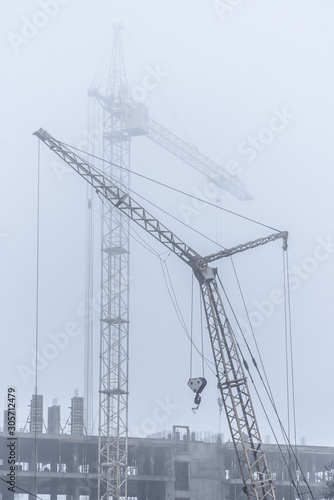 Construction crane in foggy weather on the construction of residential buildings.