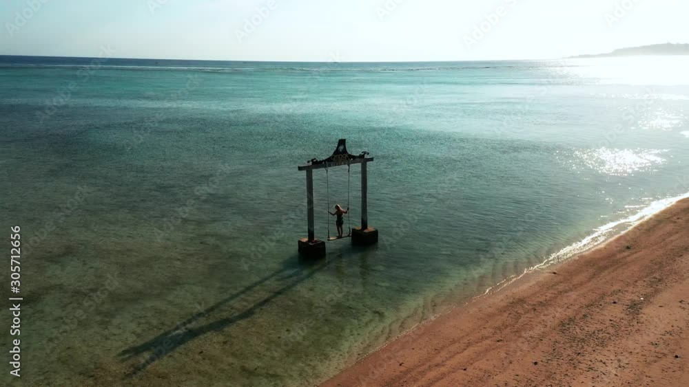 Tropical Paradise Aerial Scene, Female Figure on Swing in Bali Sea, Gili Island, Indonesia Tropical Paradise Aerial Scene, Female Figure on Swing in Bali Sea, Gili Island, Indonesia