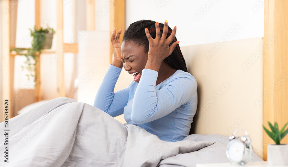 Emotional Black Woman Screaming Covering Ears Sitting In Bedroom Emotional Black Woman Screaming Covering Ears Sitting In Bedroom