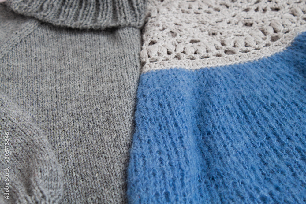 Two knitted pullovers gray with a high neck and blue with openwork knit lie next to each other Two knitted pullovers gray with a high neck and blue with openwork knit lie next to each other