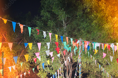 Many multicolored triangle flags hanging on a wire in the night