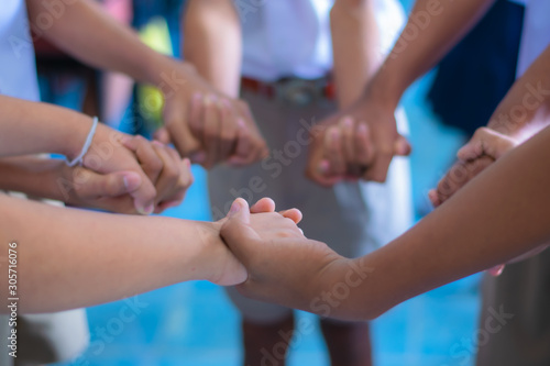 Children are standing, holding hands in a circle to play school activities.