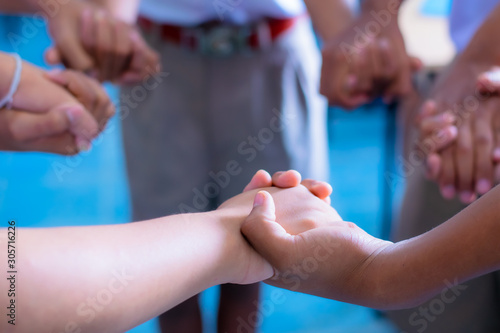 Children are standing, holding hands in a circle to play school activities.