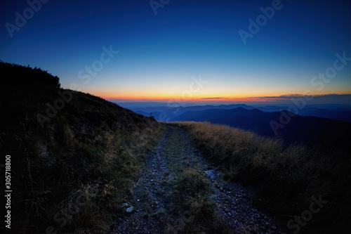 Beautiful sunrise over the mountain peaks and hills panorama, autumn rural landscape with dawn sky. Adventure mountain trekking. Moody light. Panoramic background