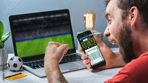 Konstfotografi Guy being happy winning a bet in online sport gambling application on his mobile