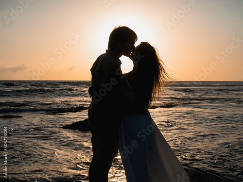 Attractive couple on vacation on the shore of the ocean at sunset time