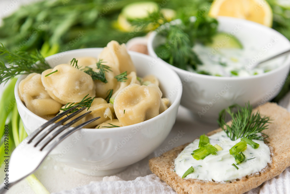 white plate with boiled dumplings with herbs and cream sauce white plate with boiled dumplings with herbs and cream sauce