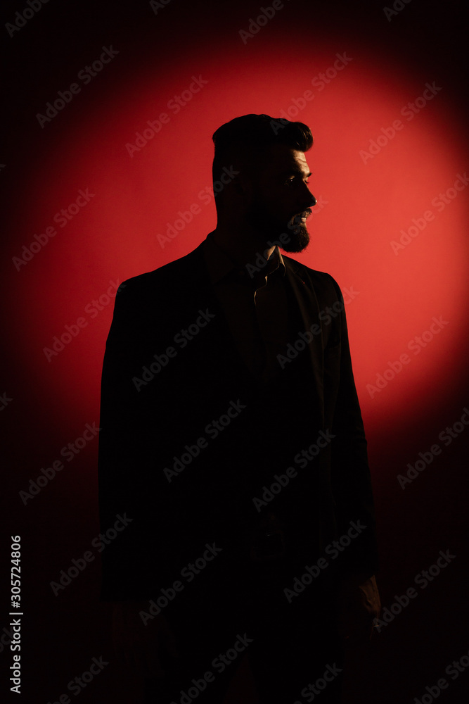 Dark male silhouette. Silhouette of man with beard over red background with copy space