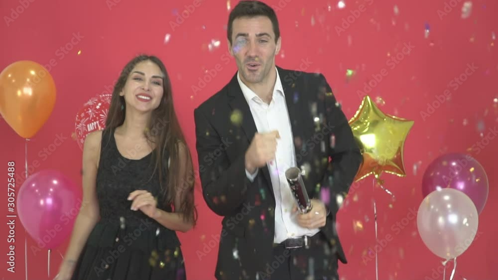 Slow motion - Happy couples dance happily, with New Year's decorations and red backgrounds. And colorful paper falling into the foreground. Slow motion - Happy couples dance happily, with New Year's decorations and red backgrounds. And colorful paper falling into the foreground.