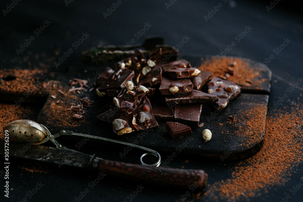 Slices of milk chocolate with nuts and dried fruits on a wooden board Slices of milk chocolate with nuts and dried fruits on a wooden board