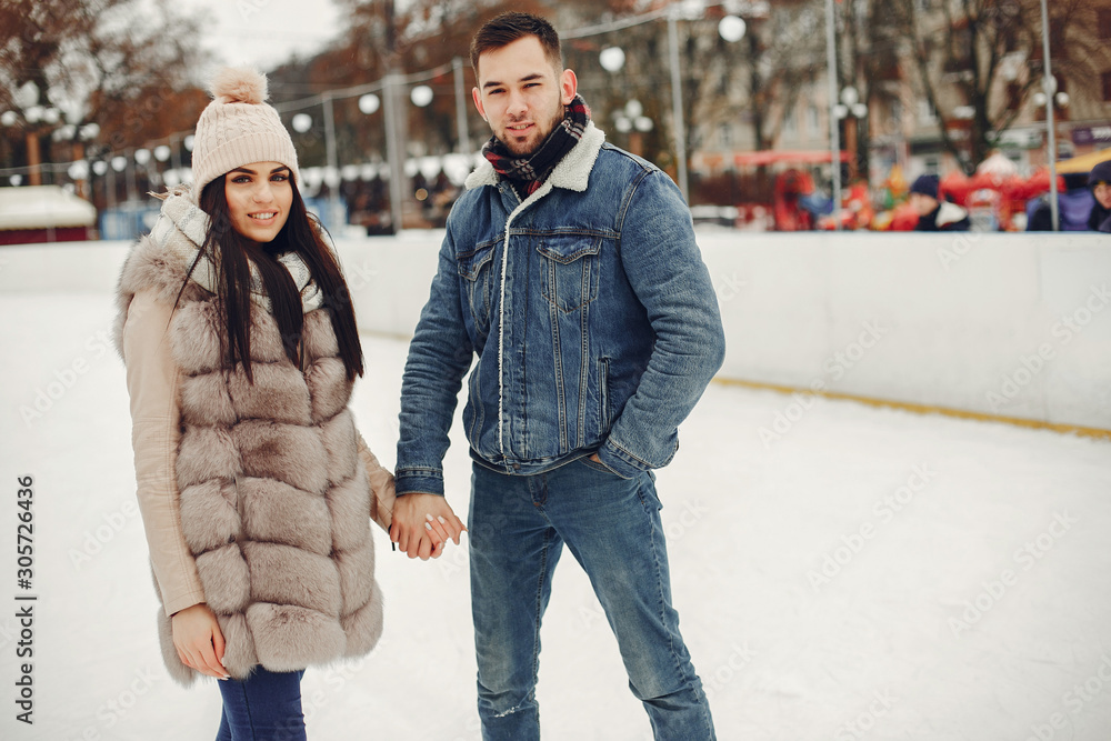Beautiful couple have fun in a ice arena. Elegant girl in a fur coat. Man in a jeans jacket Beautiful couple have fun in a ice arena. Elegant girl in a fur coat. Man in a jeans jacket