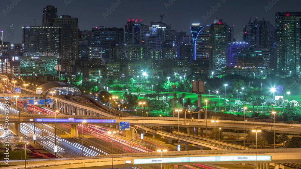 Fototapeta premium Dubai Golf Course with a cityscape of Gereens and tecom districts at the background aerial night timelapse