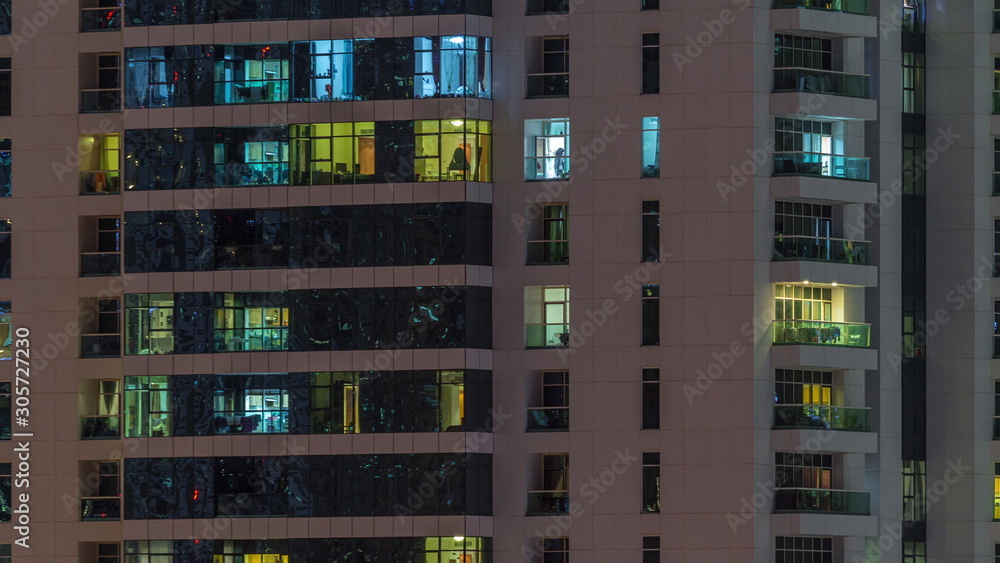 Rows of glowing windows with people in apartment building at night. Rows of glowing windows with people in apartment building at night.