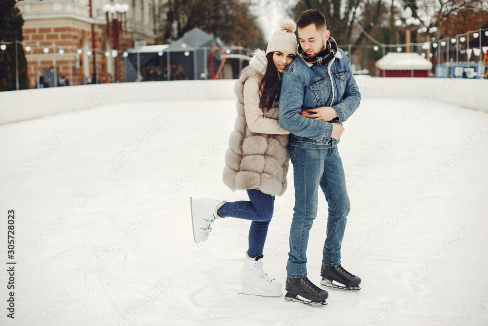 Beautiful couple have fun in a ice arena. Elegant girl in a fur coat. Man in a jeans jacket