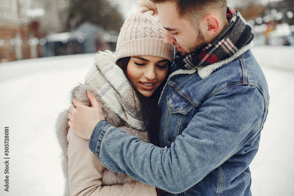 Obraz premium Couple in a winter park. Beautiful girl in a fur coat. Man in a jeans jacket.