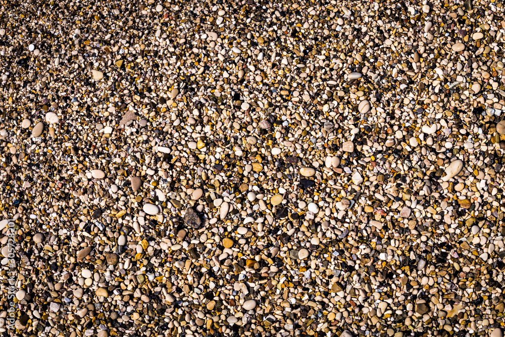 Background of multicolored sea pebbles on the beach. Small color wet stones gravel texture background. Background of multicolored sea pebbles on the beach. Small color wet stones gravel texture background.