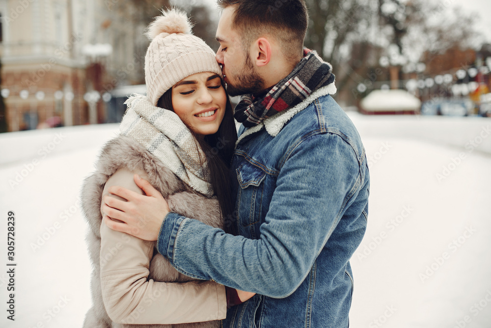 Couple in a winter park. Beautiful girl in a fur coat. Man in a jeans jacket.