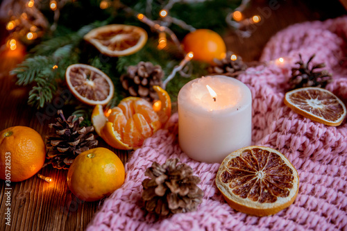 Christmas and new year decor. Christmas card. Tangerines, candle, lights, cones on a wooden background